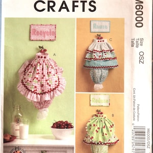 May include: McCall's Crafts sewing pattern M6000 featuring three fabric designs. The designs include a pink cherry print, a blue and white floral print, and a green cherry print. The word "Recycle" is printed on a pink fabric sign.