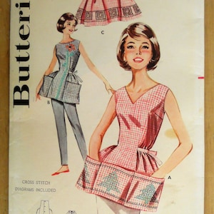 May include: Butterick sewing pattern 9982 for a sleeveless top and apron. The illustration shows a pink gingham top with a cross-stitch tree design and a blue gingham top with a flower design. Includes cross-stitch diagrams.