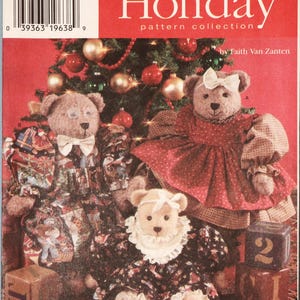 May include: A Simplicity Holiday pattern collection envelope 7452 featuring three teddy bears in festive outfits. One bear wears a holiday print dress and glasses, another a red dress with a white bow, and the third a dark dress with a white lace collar.