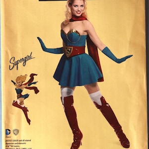 May include: A Simplicity sewing pattern envelope for a DC Comics Bombshells Supergirl costume, model 8185. The yellow package features a blue strapless dress with a red belt, a red cape, blue gloves, white stockings, and red boots.