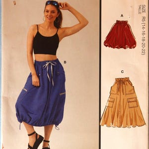May include: McCall's sewing pattern M8452 featuring a woman modeling a black crop top and blue pants. The pattern includes illustrations of a red skirt and tan pants. The text "Designed and printed in USA" is visible.