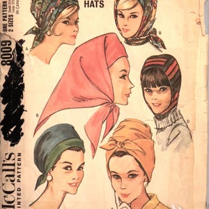 May include: Vintage McCall's pattern 8009 featuring illustrations of four different quickie hats. The hats include a paisley scarf, a headscarf, a turban, and a striped hat. The pattern includes two sizes: small 21 ½"-22" and large 22"-23".