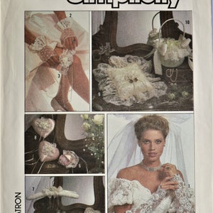 May include: Simplicity pattern 8530 for wedding accessories including lace gloves, a garter, a ring pillow, a basket, heart-shaped sachets, a padded hanger, decorated shoes, and a small pouch. The envelope features illustrations of these items.