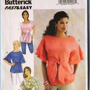 May include: A Butterick B6685 sewing pattern envelope featuring illustrations and a photograph of a top with a tie waist and tiered flutter sleeves. The designs include a striped version, a solid coral version, a blue version, and a floral print version.