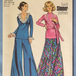 May include: A Simplicity 5743 sewing pattern envelope featuring illustrations of two outfits. One is a solid blue long-sleeve top with white ruffled trim and matching wide-leg pants. The other is a pink long-sleeve top with a belt and patterned pants.