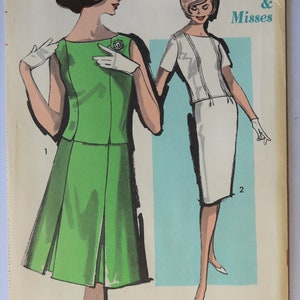 May include: Vintage sewing pattern featuring illustrations of two dresses. One is a green dress with a pleated skirt, the other is a white dress. The pattern is labeled "Sew-Easy Advance" and includes the text "Junior & Misses" and size 13.