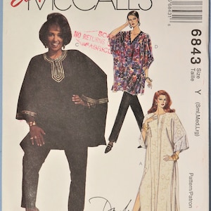 May include: Easy McCall's 6843 sewing pattern envelope featuring illustrations of three garments: a black tunic with gold trim, a purple floral print kaftan, and a long white dress with a subtle swirl pattern. The text includes the brand name, pattern number 6843, size Y, and the name Daphne Maxwell Reid.