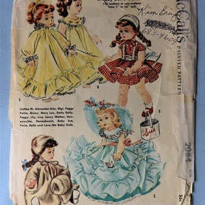May include: A vintage McCall's printed pattern envelope for Chubby Doll's Wardrobe, featuring illustrations of dolls in various outfits including yellow dresses, a red checkered dress, and a blue ruffled dress with a matching hat and a bucket labeled Sue.