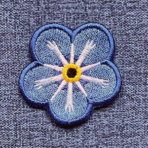 May include: A blue embroidered forget-me-not flower patch with a yellow centre and white petals.