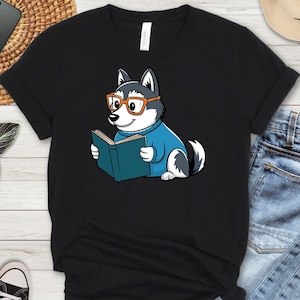 May include: Black t-shirt with a cartoon husky wearing glasses and reading a book. The husky is wearing a blue sweater.