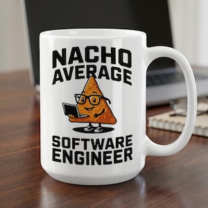 Könnte beinhalten: Ein weißer Keramikbecher mit einer Grafik eines Cartoon-Nachos, das eine schwarze Brille trägt und einen Laptop benutzt. Der Text darüber lautet NACHO AVERAGE und der Text darunter lautet SOFTWARE ENGINEER in fetten schwarzen Großbuchstaben.