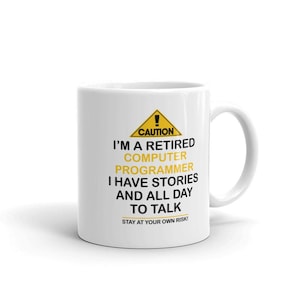 May include: White ceramic coffee mug with a yellow caution sign and black text that reads: "CAUTION I'M A RETIRED COMPUTER PROGRAMMER I HAVE STORIES AND ALL DAY TO TALK STAY AT YOUR OWN RISK!"