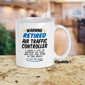 May include: White ceramic mug with the text "WARNING RETIRED AIR TRAFFIC CONTROLLER" in blue and black. The mug also includes the text "I HAVE A LOT OF STORIES TO TELL AND ALL THE TIME IN THE WORLD. YOU HAVE BEEN WARNED!"