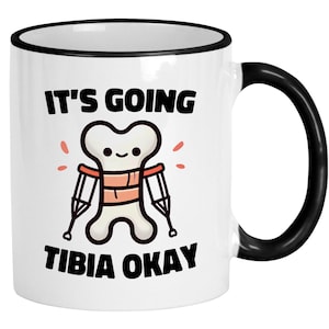May include: White ceramic coffee mug with a black rim and handle. The mug has a cartoon image of a bone with crutches and the text "It's going tibia okay".