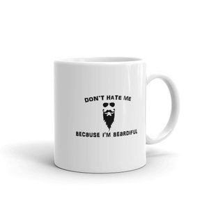 May include: White ceramic mug with a black graphic of a beard wearing sunglasses and a mustache. The text on the mug reads "DON'T HATE ME BECAUSE I'M BEARDIFUL". The mug has a curved handle.