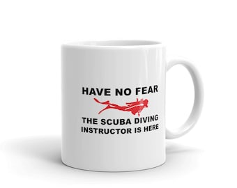 May include: White ceramic mug with a black and red design. The mug has the text "HAVE NO FEAR THE SCUBA DIVING INSTRUCTOR IS HERE" and a red silhouette of a scuba diver.