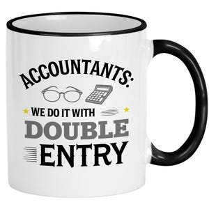May include: White ceramic coffee mug with a black rim and handle. The mug has a black graphic that says "Accountants: We do it with double entry". The graphic also includes a pair of glasses and a calculator.