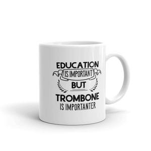 May include: White ceramic mug with black text that reads "Education is important but trombone is importanter".