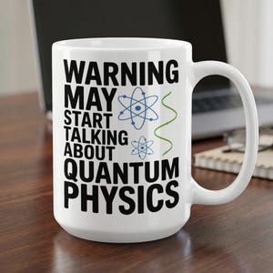 May include: A white ceramic mug featuring the black text WARNING MAY START TALKING ABOUT QUANTUM PHYSICS, accompanied by two blue atom symbols and a green wavy line graphic printed on the front surface of the cylindrical drinking vessel.