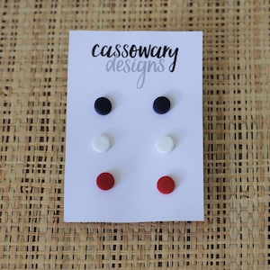 May include: A set of six stud earrings in red, white, and blue. The earrings are displayed on a white card with the text "cassowary designs".