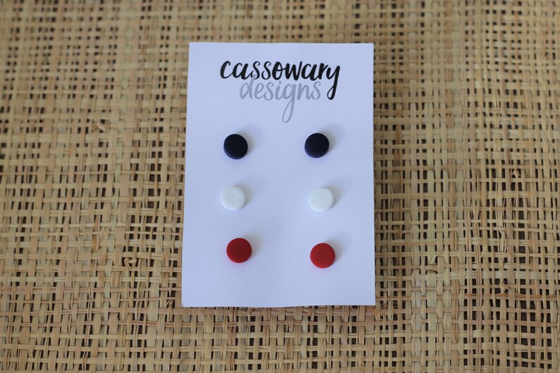 May include: A set of six stud earrings in red, white, and blue. The earrings are displayed on a white card with the text "cassowary designs".