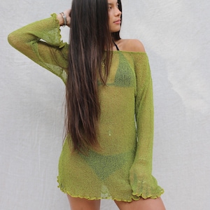 May include: A lime green, off-the-shoulder cover-up dress with long sleeves and a ruffled hem. The see-through knit fabric reveals a green bikini underneath. The model has long, dark hair.