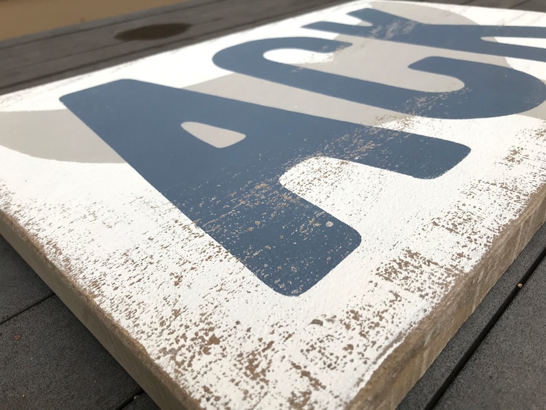 May include: A wooden sign with the word "ACE" painted in blue on a white background. The sign has a distressed, rustic look with a light brown stain.