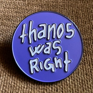 May include: A purple round pin with white text that reads "Thanos was right".