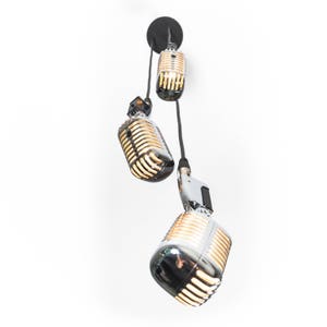May include: Three vintage-style microphones hanging from the ceiling, each with a chrome finish and a warm, yellow light emanating from the inside.