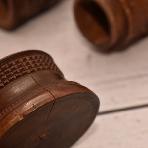 May include: A close-up of a wooden, brown, round, decorative object with a carved pattern. The object is split in half, revealing the inside.