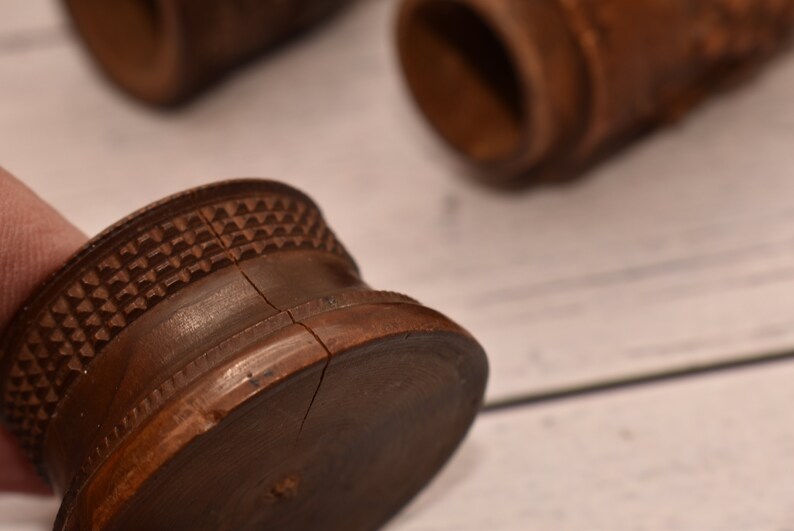 May include: A close-up of a wooden, brown, round, decorative object with a carved pattern. The object is split in half, revealing the inside.