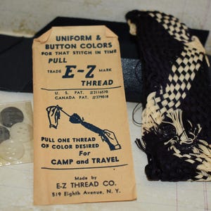 May include: Vintage sewing kit with a packet of E-Z Thread, buttons, and a woven black and white trim. The thread packet reads "Uniform & Button Colors" and includes the text "Pull one thread of color desired for camp and travel."