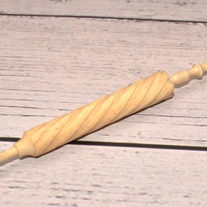 Puede incluir: Una herramienta de marfil blanco, tallada a mano, en forma de espiral con un pomo en un extremo.
