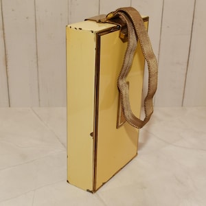 May include: A vintage rectangular handbag with a pale yellow exterior and gold-toned metal trim. The bag features a matching gold mesh handle and a clasp closure. The bag's design is simple and elegant, suggesting a classic style.