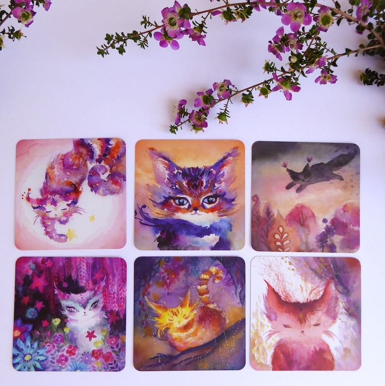 Pode incluir: Seis aquarelas de gatos com fundos diferentes. As pinturas est&atilde;o em cart&otilde;es quadrados com bordas brancas. Os gatos s&atilde;o retratados em v&aacute;rias poses e cores, incluindo roxo, rosa, laranja e preto.