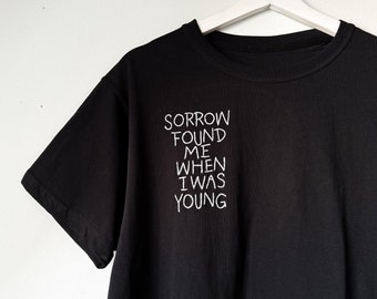 Handbroderad svart t-shirt med The National-motivet "Sorgen fann mig när jag var ung", för musikälskare