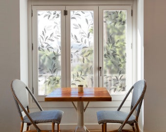 May include: A small wooden table with two chairs sits in front of a window with a floral patterned privacy film. The chairs are wicker with blue cushions.