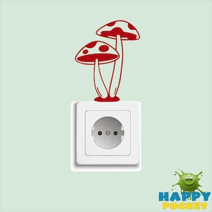May include: A white electrical outlet with a red mushroom sticker on it. The sticker features two mushrooms with white spots.