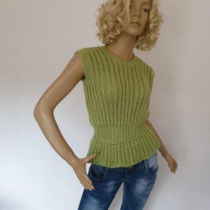May include: A sleeveless, lime green knitted top with a ribbed texture. The top features a fitted waist and a round neckline. The garment is displayed on a mannequin wearing blue jeans.