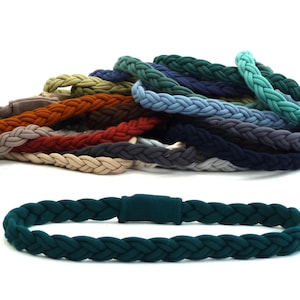 May include: A collection of braided fabric headbands in various colours, including teal, blue, grey, brown, and green. The headbands are made of a soft, stretchy fabric and are perfect for adding a touch of style to any outfit.