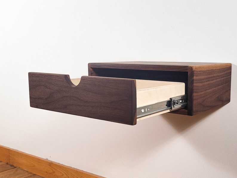 May include: A dark walnut wood floating shelf with a drawer that is partially open. The drawer is made of light wood and has a metal slide.