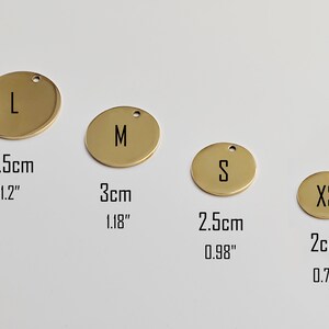May include: Four gold-colored, round metal tags with the letters L, M, S, and XS. The tags have a small hole at the top for hanging. Measurements are provided in both inches and centimeters: 1.2" (3.5cm), 1.18" (3cm), 0.98" (2.5cm), and 0.79" (2cm).