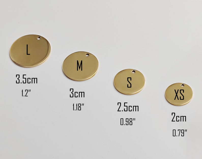 May include: Four gold-colored, round metal tags with the letters L, M, S, and XS. The tags have a small hole at the top for hanging. Measurements are provided in both inches and centimeters: 1.2" (3.5cm), 1.18" (3cm), 0.98" (2.5cm), and 0.79" (2cm).