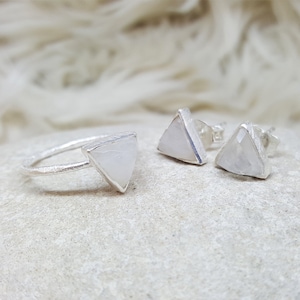 Könnte beinhalten: Ein Set aus Silberschmuck mit einem Ring und Ohrringen mit dreieckigen Mondstein-Akzenten.