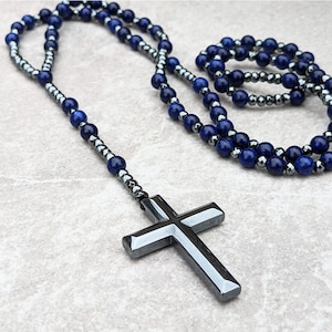 May include: A dark blue and silver beaded necklace with a large silver cross pendant.