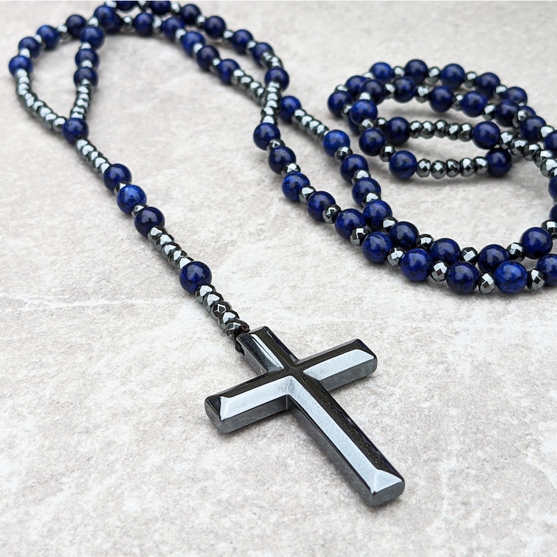 May include: A dark blue and silver beaded necklace with a large silver cross pendant.