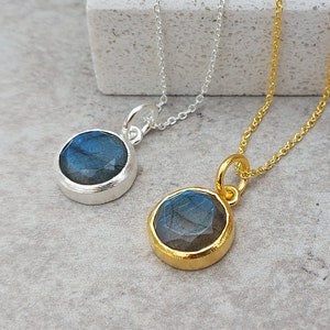 May include: Two silver necklaces with round labradorite gemstone pendants. One necklace has a silver chain and the other has a gold chain.