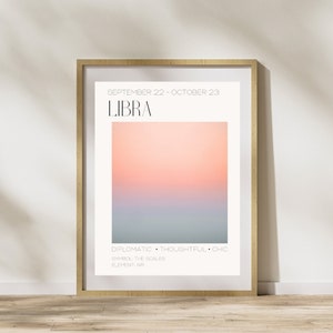 May include: A framed poster with a pink and blue gradient background. The poster features the text "SEPTEMBER 22 - OCTOBER 23" and "LIBRA" in black. Below the gradient, the text "DIPLOMATIC THOUGHTFUL CHIC" is in black. The text "SYMBOL THE SCALES" and "ELEMENT: AIR" are also in black.