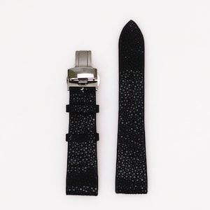 May include: Black leather watch strap with a silver buckle. The strap has a textured, pebbled surface.