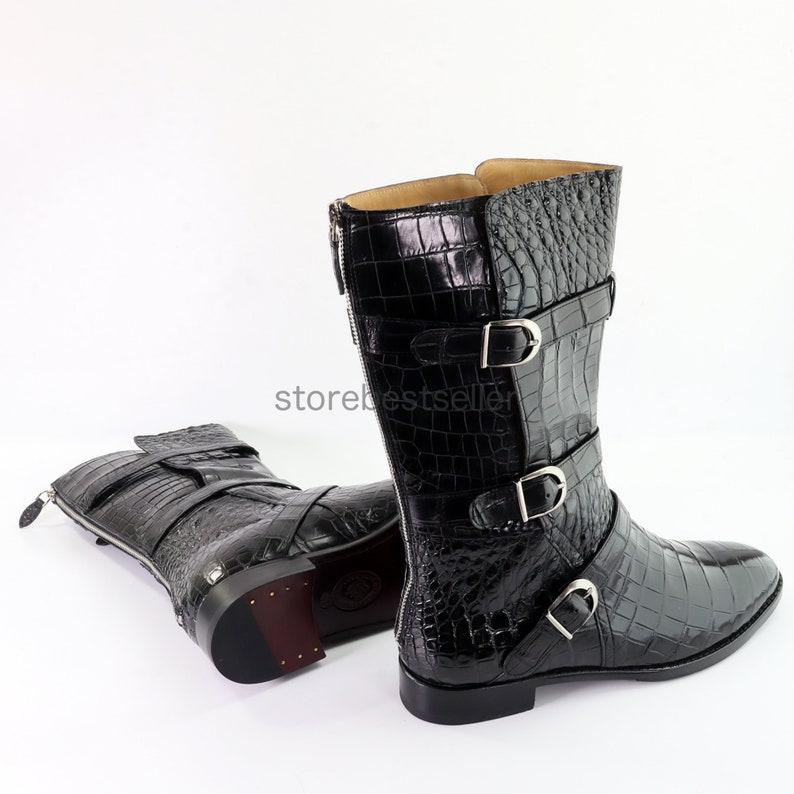 May include: Black leather boots with a crocodile pattern and multiple buckles. The boots have a pointed toe and a side zipper.